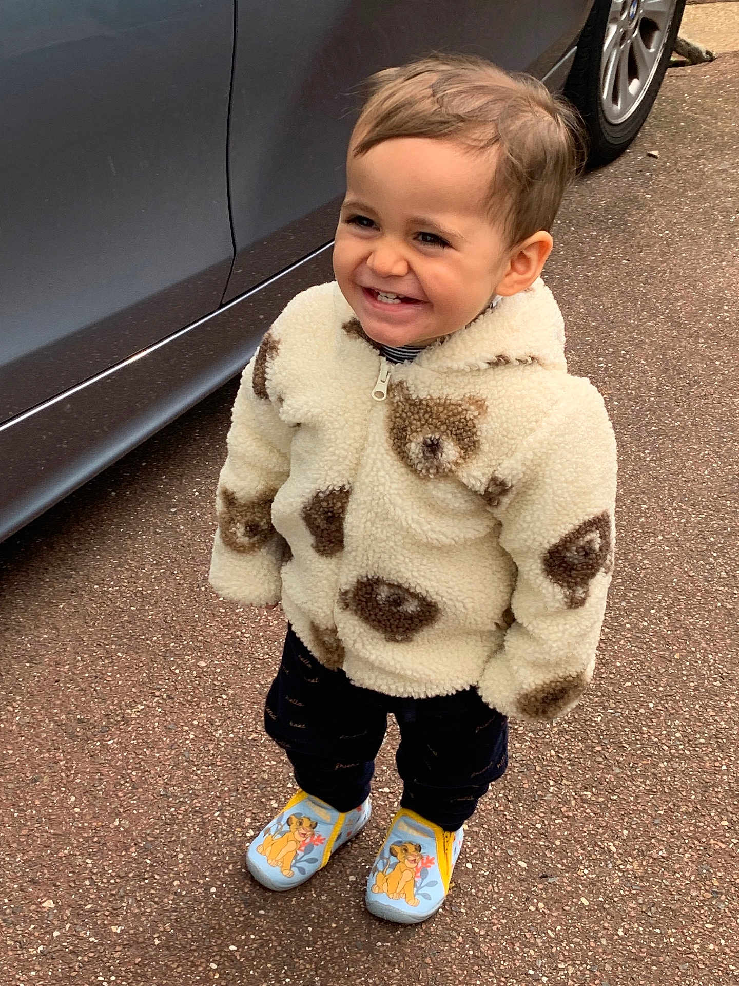 Angelo participe au concours pour gagner de l'argent avec cette photo : toddler, child, smiling, jacket, teddy_bear_pattern, footwear, slippers, cartoon_character, outdoor, pavement, car, vehicle, standing, happy, cute, portrait, clothing, warm_clothes, young_child, person