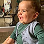 Angelo a rejoint le concours — aidez-le/la à gagner de superbes lots ! baby, child, smiling, high_chair, green_shirt, gray_vest, indoor, kitchen, table, chair, happy, face, person, cute, toddler, infant, expression, seat, home, light