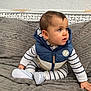 Angelo participe au concours pour gagner de l'argent avec cette photo : baby, child, infant, striped_clothing, blue_vest, sitting, couch, blanket, indoor, curious, cute, footwear, white_shoes, soft_texture, home, young_child, person, portrait, looking_away, cozy