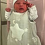 baby, child, cozy, crib, cute, face, hand, hat, indoor, infant, lying_down, metal_frame, moons, newborn, person, pink_blanket, sleeping_bag, soft, stars, white_clothing