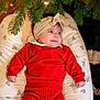 Aminaya a rejoint le concours — aidez-le/la à gagner de superbes lots ! baby, red_clothing, headband, cushion, christmas_tree, greenery, indoor, infant, knitwear, holiday, decor, child, smiling, cozy, soft_lighting, floor_rug, portrait, cute, festive, relaxed