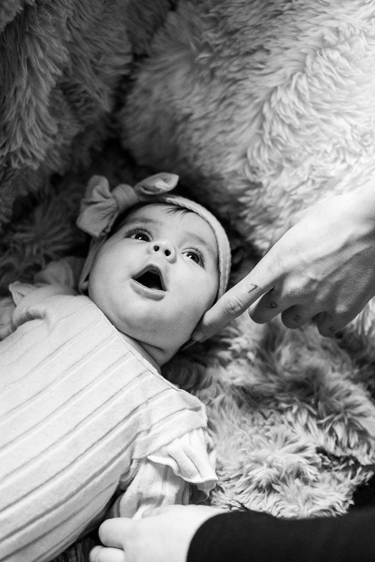 Aminaya participe au concours pour gagner de l'argent avec cette photo : baby, infant, headband, face, hand, finger, tattoo, black_and_white, portrait, expression, cozy, soft_texture, clothing, lying_down, cute, child, person, closeup, indoors, curious