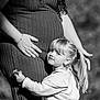 child, pregnant_woman, hugging, flowers, black_and_white, mother, pregnancy, outdoor, portrait, love, family, toddler, girl, hand, dress, long_hair, nature, affection, happy, casual_clothing