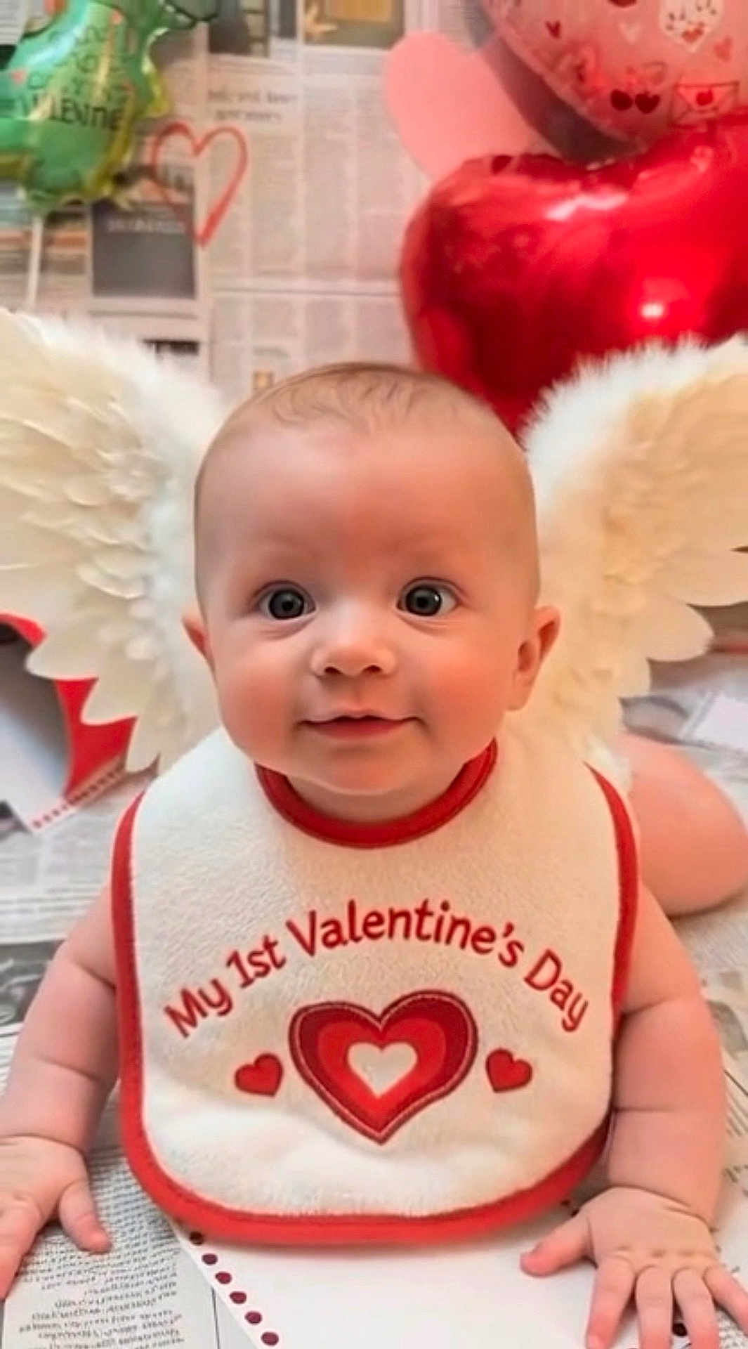 Gabriel joined the competition — help win amazing prizes! baby, infant, valentines_day, bib, heart, balloon, angel_wings, smiling, cute, celebration, holiday, love, red, white, face, child, portrait, indoors, hands, newborn