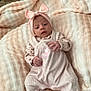 baby, infant, pink, headband, bow, blanket, soft_texture, clothing, onesie, cute, lying_down, indoors, cozy, portrait, child, newborn, sleepwear, face, hands, footed_pajamas