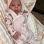 baby, infant, pink_bow, headband, blanket, soft_texture, gingham, floral_pattern, long_sleeve, onesie, cute, child, newborn, lying_down, indoors, carpet, relaxed, portrait, hand, face