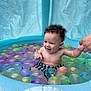 toddler, child, pool, water_balloons, inflatable_pool, curly_hair, smiling, holding_hand, summer, fun, water, play, outdoor, colorful, swimming, cute, baby, checkered_shorts, skin, happy