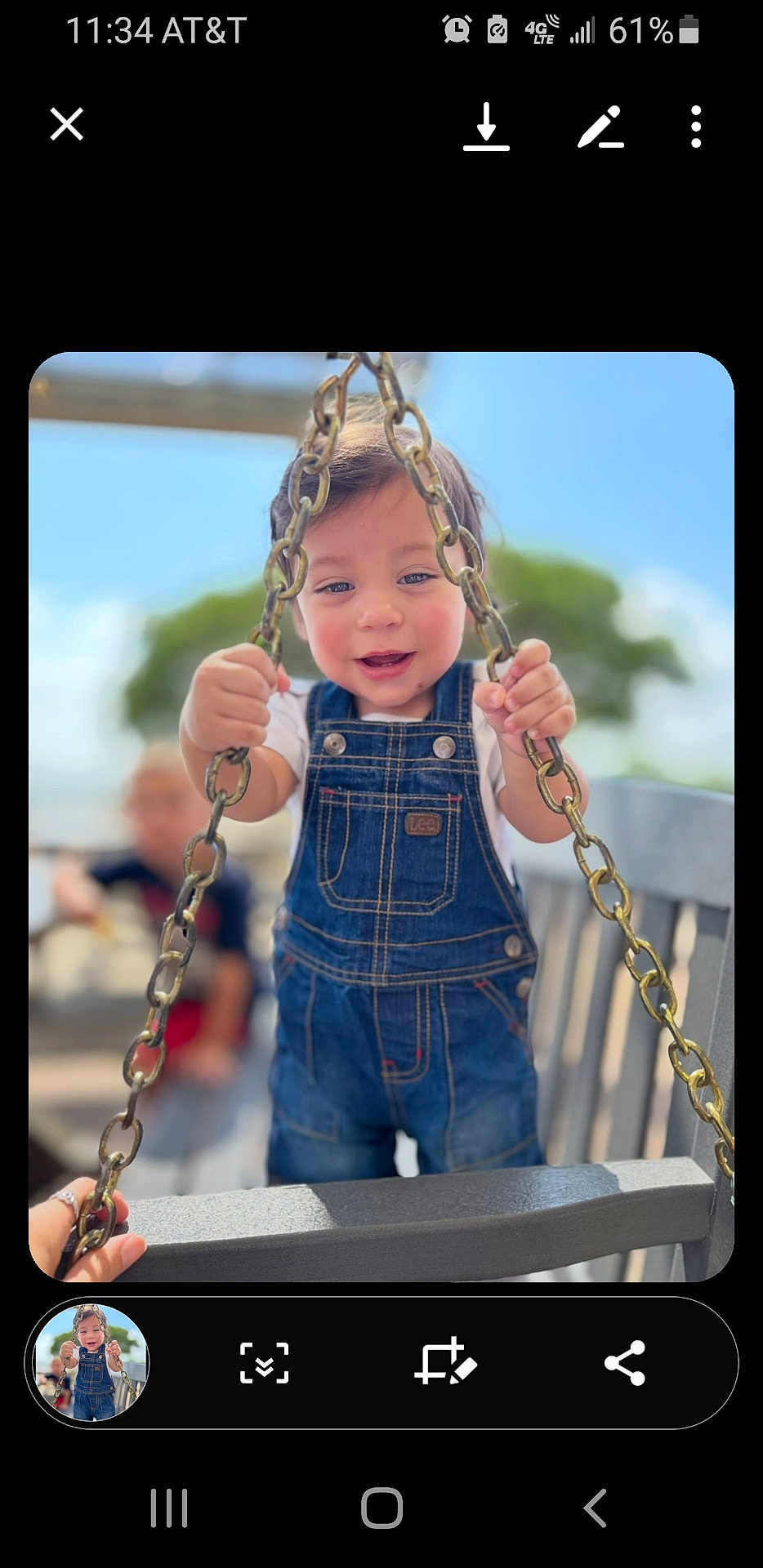 Niko is registered to the contest to win money with this photo: child, toddler, swing, chains, denim_overalls, smiling, outdoor, daylight, playground, person, happy, holding, blurred_background, tree, hand, blue_sky, casual_clothing, cute, young_child, fun