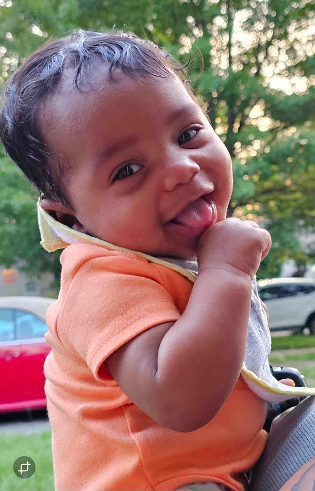 Marshall joined the competition — help win amazing prizes! baby, child, tongue_out, orange_shirt, outdoor, greenery, smiling, cute, infant, portrait, hand, face, person, daylight, trees, car, happy, nature, closeup, skin