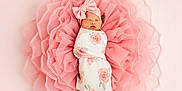 Juniper is registered to the contest to win money with this photo: baby, newborn, infant, swaddled, headband, bow, floral_swaddle, pink, tulle, ruffles, blanket, sleeping, portrait, studio, soft_light, top_view, flower, delicate, peaceful, one_person