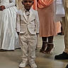 child, boy, white_suit, dress, girl, tiara, people, party, celebration, indoor, formal_wear, shoes, floor, standing, person, adult, family, event, smile, hair