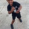 child, smiling, black_clothing, shorts, sneakers, outdoor, concrete, happy, motion_blur, portrait, person, playful, daylight, short_hair, active, young, casual, toddler, fun, joy