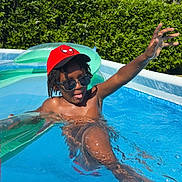 Leodrick is registered to the contest to win money with this photo: child, pool, water, sunglasses, red_cap, summer, playful, sunny, outdoor, hedge, house, inflatable, swimming, fun, daylight, person, blue_sky, relaxation, casual, child_playing