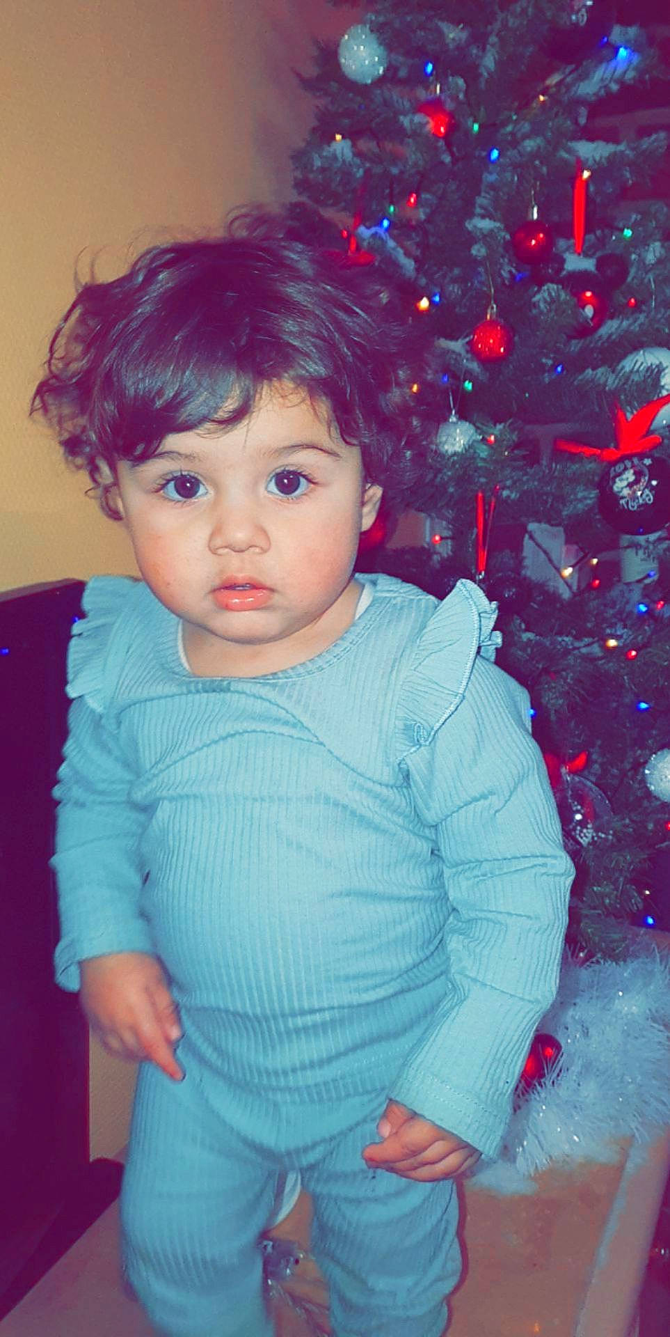 Ines a rejoint le concours — aidez-le/la à gagner de superbes lots ! baby_toddler_clothing, blue, cheek, christmas_tree, electric_blue, eye, facial_expression, happy, head, holiday_ornament, human_body, iris, lip, ornament, person, plant, skin, sleeve, standing, toddler