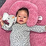 Kehlani is registered to the contest to win money with this photo: baby, infant, child, lying_down, pink_blanket, plush_toy, elephant_toy, leopard_print, onesie, pacifier, smiling, face, portrait, indoor, textile, soft_blanket, arms_outstretched, dark_hair, crib, cozy