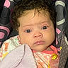 baby, infant, child, portrait, face, eyes, curly_hair, looking_at_camera, serious, carrier, blanket, pacifier, clothing, pink, patterned, indoor, close_up, seated, soft_blanket, photography