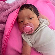 Kehlani joined the competition — help win amazing prizes! baby, infant, child, portrait, sleepy, pacifier, pink, blanket, bed, bedding, onesie, clothing, lying_down, indoor, cozy, face, hair, eyes, newborn, close_up