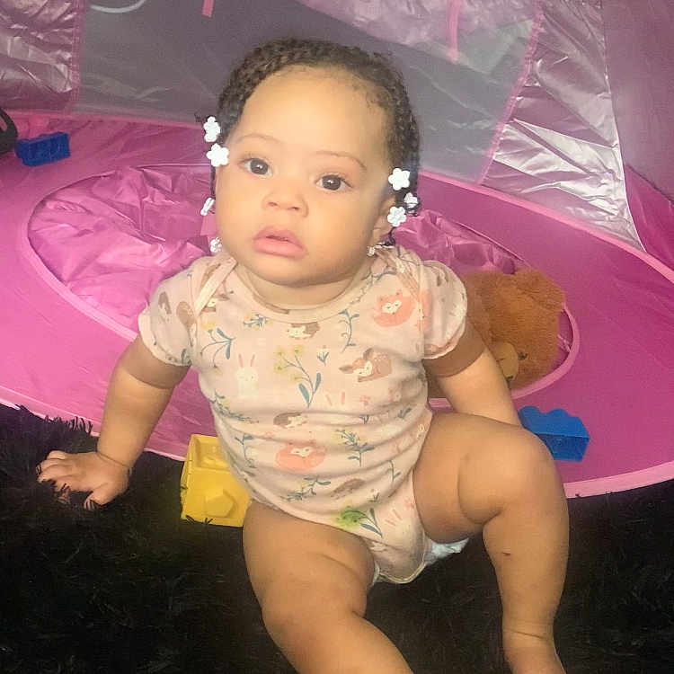 Kehlani joined the competition — help win amazing prizes! baby, child, infant, sitting, portrait, face, eyes, serious_expression, curly_hair, hair_bows, pink, play_tent, toy, teddy_bear, building_blocks, indoor, carpet, clothing, barefoot, photography