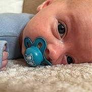 Rue is registered to the contest to win money with this photo: baby, pacifier, blue_clothing, closeup, face, infant, soft_texture, fluffy_surface, hand, skin, eyes, lying_down, cute, indoors, peaceful, toddler, sleepy, portrait, child, cozy