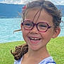 child, girl, smile, glasses, curly_hair, outdoor, lake, grass, happy, portrait, face, earrings, nature, daylight, casual_clothing, eyewear, closeup, joyful, summer, playful