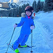 Azilys participe au concours pour gagner de l'argent avec cette photo : child, skiing, snow, mountain, winter, blue_jacket, ski_poles, helmet, gloves, pine_trees, ski_boots, snowy_slope, outdoor, smiling, cold_weather, recreation, snow_sports, nature, clear_sky, person