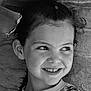 child, girl, smile, portrait, black_and_white, face, hair, leaf, stone_wall, texture, young, eyes, expression, outdoor, natural_light, freckles, casual, happy, curly_hair, profile