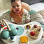 Maël a rejoint le concours — aidez-le/la à gagner de superbes lots ! baby, smiling, activity_center, toy, indoor, child, happy, play, floor, clothing, bib, furniture, couch, tile_floor, person, infant, cute, home, seat, toddler