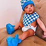 baby, infant, child, diaper, bib, hat, booties, blue_hat, checkered_bib, blue_booties, couch, upholstery, sitting, portrait, face, big_eyes, skin, cute, indoor, adorable