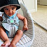 baby, child, infant, hat, cap, baby_seat, car_seat, blue_clothing, straps, indoor, carpet, door, curious_expression, sitting, barefoot, person, young_child, cushion, home_interior, cute