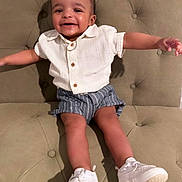 Kai Eli is registered to the contest to win money with this photo: toddler, child, smiling, happy, sitting, couch, tufted_couch, white_shirt, striped_shorts, white_shoes, footwear, person, indoor, portrait, cute, baby, fashion, casual, joy, arms_outstretched