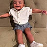 toddler, child, smiling, happy, sitting, couch, tufted_couch, white_shirt, striped_shorts, white_shoes, footwear, person, indoor, portrait, cute, baby, fashion, casual, joy, arms_outstretched