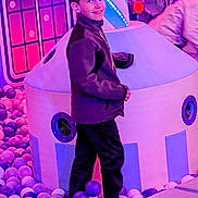 Giovanni is registered to the contest to win money with this photo: child, boy, smiling, ball_pit, play_area, indoor, colorful, purple, pink, jacket, pants, toy, play_structure, fun, leisure, recreation, happy, person, lighting, entertainment