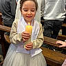 child, girl, candle, white_dress, smile, church, pew, people, celebration, happy, portrait, indoors, event, holding, light, clothing, young, person, hand, long_hair