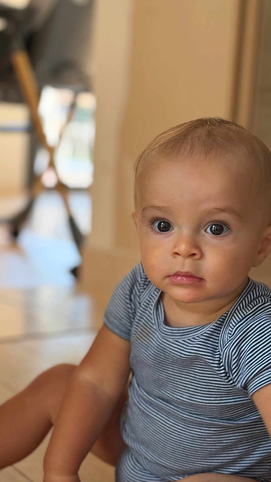 Lelio participe au concours pour gagner de l'argent avec cette photo : baby, child, infant, face, eyes, striped_clothing, onesie, sitting, floor, indoor, portrait, cute, curious, skin, head, person, young, expression, closeup, blurred_background
