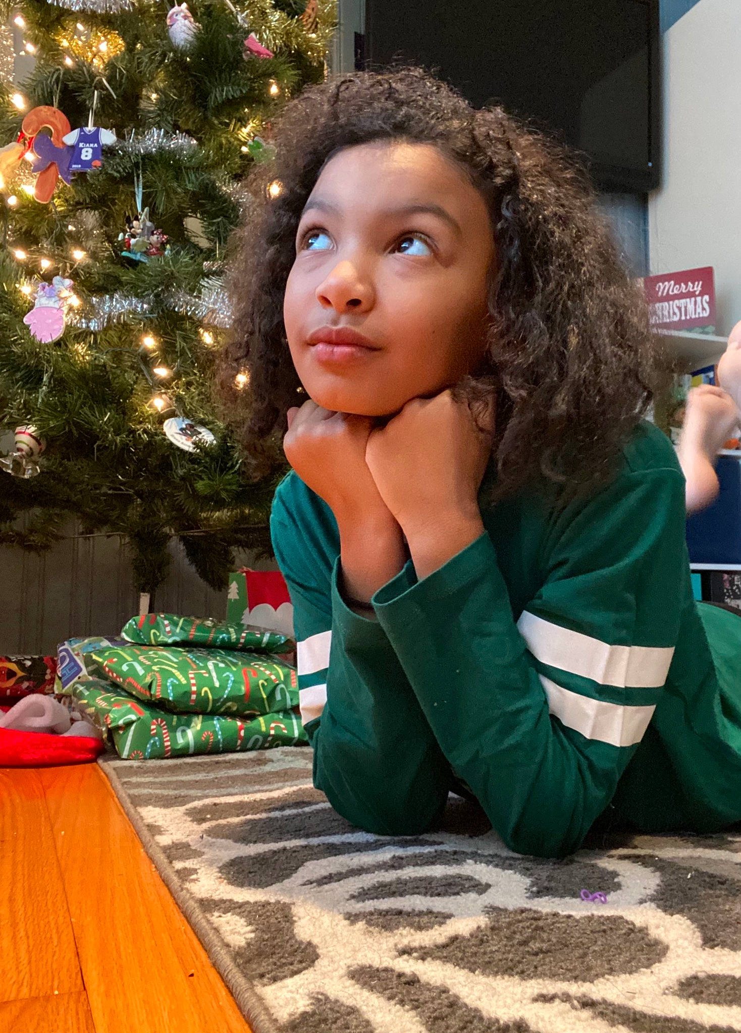 Kiana is registered to the contest to win money with this photo: brown_hair, christmas_ornament, christmas_tree, conifer, event, eyewear, flooring, fun, grass, hair, happy, holiday, holiday_ornament, leisure, ornament, person, room, sitting, street_fashion, t_shirt