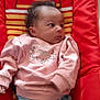 baby, infant, child, pink_sweater, blue_pants, curly_hair, baby_seat, striped_pattern, bear_design, red, yellow, indoor, portrait, clothing, cute, lying_down, young_child, face, looking_sideways, soft_fabric