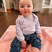 Alayna is registered to the contest to win money with this photo: baby, child, girl, purple_bow, lilac_sweater, floral_pants, white_shoes, pink_blanket, wooden_floor, colorful_block, indoor, living_room, furniture, smiling, cute, portrait, seated, person, toy, home