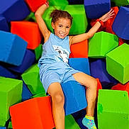 Daelyne is registered to the contest to win money with this photo: child, smiling, foam_blocks, colorful, play_area, blue_shorts, blue_shirt, socks, happy, indoor, playful, fun, foam_cubes, arms_up, casual_clothing, kid, joyful, relaxed, bright_colors, leisure