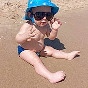 Sajed a rejoint le concours — aidez-le/la à gagner de superbes lots ! baby, child, beach, sand, sunglasses, hat, sunny, water, summer, outdoor, cute, skin, barefoot, fun, vacation, play, sunhat, blue, infant, toddler