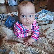 Iyana is registered to the contest to win money with this photo: baby, baby_car_seat, bed, blanket, blue_eyes, child, furniture, home, indoor, infant, lying_down, photography, pink_clothing, portrait, serious_expression, sitting, soft_texture, striped_clothing, wide_eyes, wooden_floor