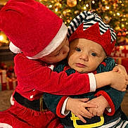Lowen participe au concours pour gagner de l'argent avec cette photo : toddler, child, christmas_costume, santa_hat, elf_costume, holiday, christmas_tree, christmas_lights, gift, hug, kiss, festive, indoors, celebration, cute, smile, family, warmth, joy, seasonal