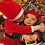 toddler, child, christmas_costume, santa_hat, elf_costume, holiday, christmas_tree, christmas_lights, gift, hug, kiss, festive, indoors, celebration, cute, smile, family, warmth, joy, seasonal