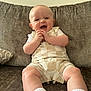 Cody is registered to the contest to win money with this photo: baby, child, smiling, sitting, romper, couch, indoor, happy, clapping, infant, cute, person, face, legs, white_socks, plush, home, joy, expression, portrait