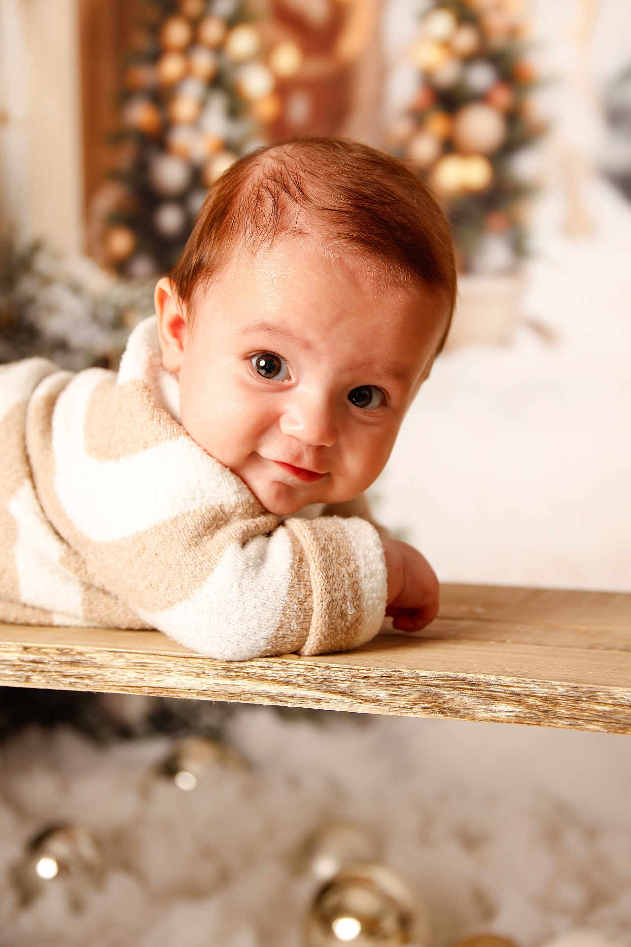 Izaac participe au concours pour gagner de l'argent avec cette photo : baby, infant, child, portrait, closeup, smile, eyes, cozy_clothing, striped_sweater, wooden_table, holiday, christmas_tree, bokeh, ornaments, warm_tones, cute, lying_down, indoors, soft_texture, festive