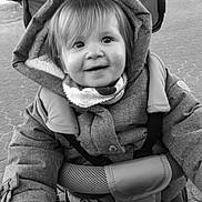 Maëlys participe au concours pour gagner de l'argent avec cette photo : child, toddler, smile, jacket, hood, scarf, stroller, handlebar, outdoor, pavement, black_and_white, happy, portrait, baby, person, cute, winter_clothing, young, face, grip