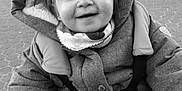 Maëlys participe au concours pour gagner de l'argent avec cette photo : child, toddler, smile, jacket, hood, scarf, stroller, handlebar, outdoor, pavement, black_and_white, happy, portrait, baby, person, cute, winter_clothing, young, face, grip