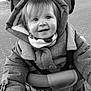 child, toddler, smile, jacket, hood, scarf, stroller, handlebar, outdoor, pavement, black_and_white, happy, portrait, baby, person, cute, winter_clothing, young, face, grip
