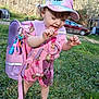 Madilynn joined the competition — help win amazing prizes! toddler, child, backpack, pink, hat, unicorn, outdoor, grass, flowers, barefoot, playful, smiling, sunlight, nature, young_child, curly_hair, casual_clothing, daytime, happy, cute