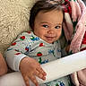 Neo joined the competition — help win amazing prizes! baby, child, infant, smiling, portrait, close_up, indoors, blanket, plush_blanket, pajamas, patterned_clothing, strawberry_pattern, toy, soft_furniture, cozy, sitting, lying_down, hand, brown_hair, happy