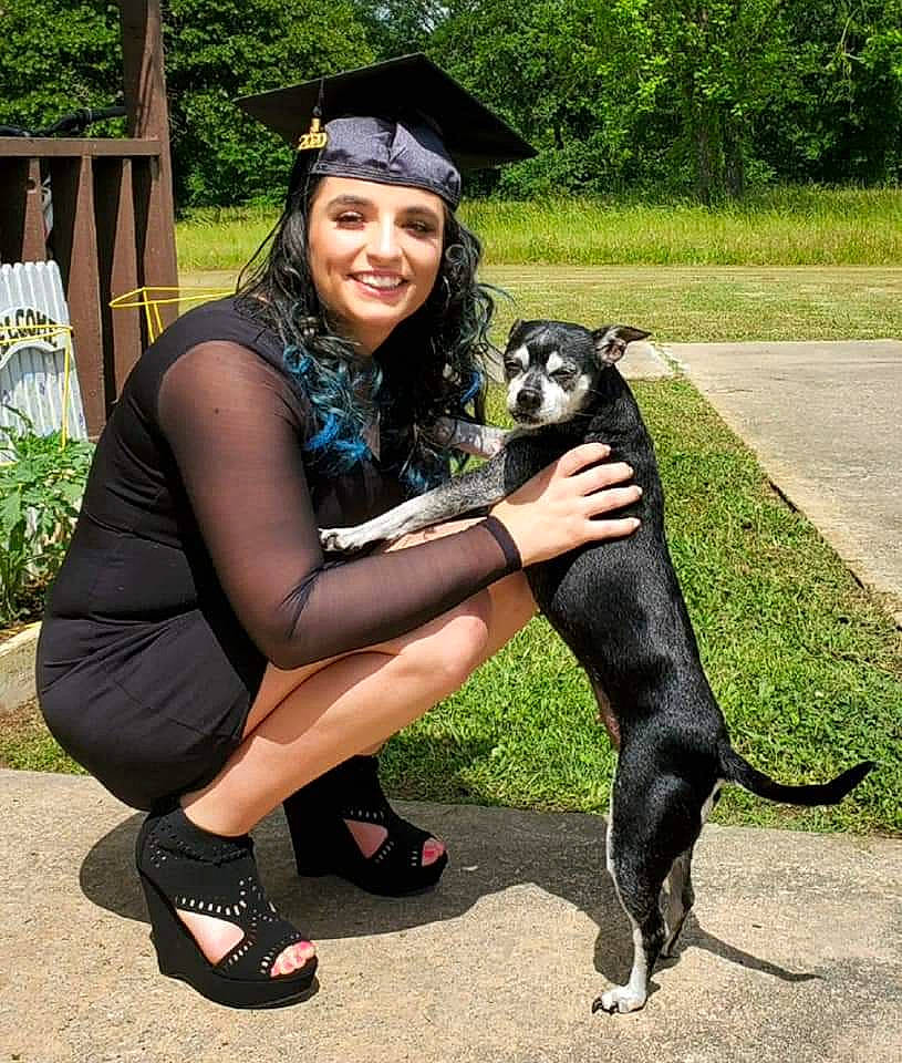 Angel is registered to the contest to win money with this photo: carnivore, companion_dog, dog, dog_breed, event, eyewear, fawn, grass, human_leg, lap, leash, leg, leisure, mortarboard, plant, sandal, shoe, smile, tail, thigh